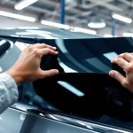 Apply window tint near me with precision in a well-lit garage environment.